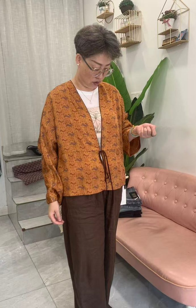 店里的新中式宽松小衫 博山玲珑服饰店内新中式小衫实拍,橘色系带上衣配阔腿裤,松弛宽松版型,位于淄博市博山区颜山商城18号